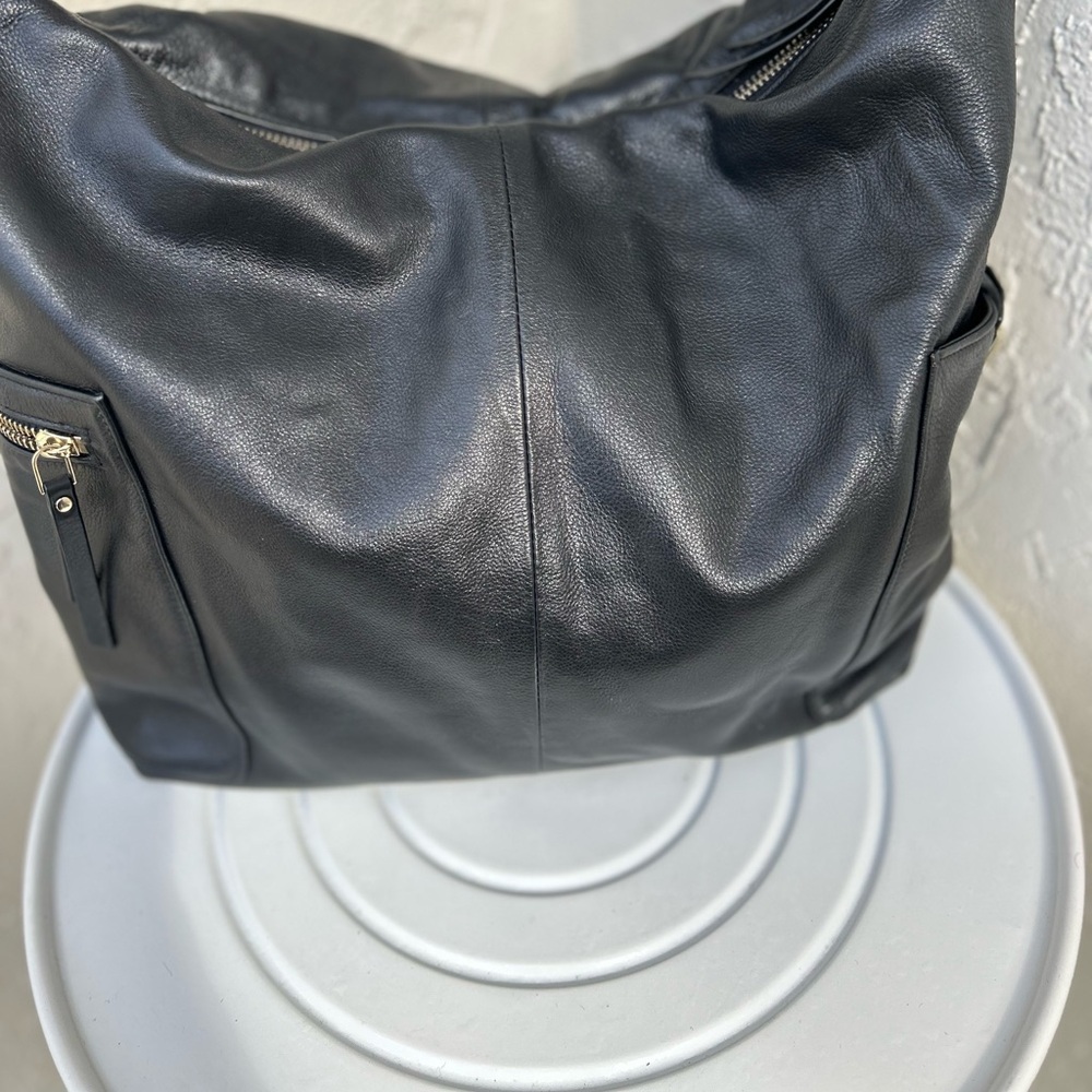 Cole Haan black leather Hobo handbag features a distinctive metal lock & Zipper